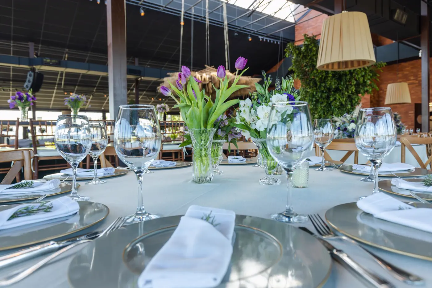 Mesa de matrimonio montada con copas, vajilla y arreglos florales